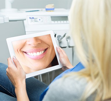 Woman looking at virtual smile design on tablet computer