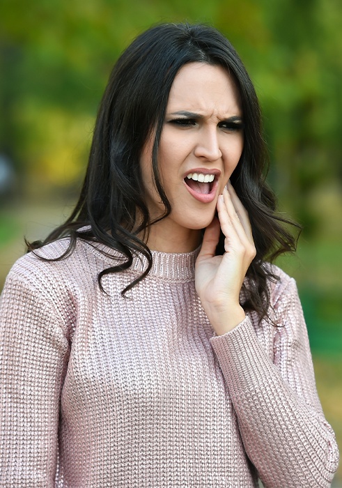 Woman in need of emergency dentistry holding jaw in pain