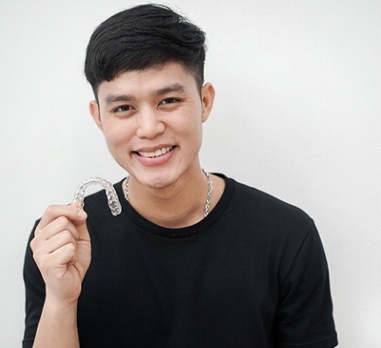 Smiling teen boy holding Invisalign in Daniel Island