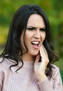 woman holding jaw in pain