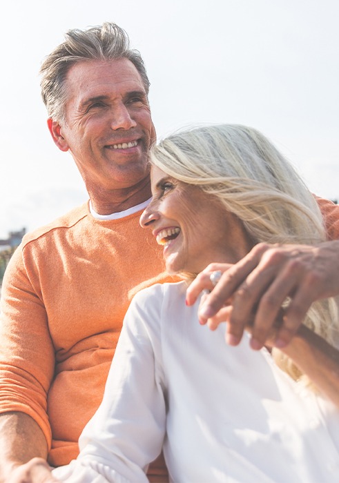 Man and woman smiling after replacing missing teeth