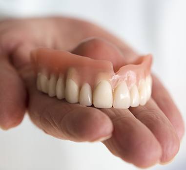 Hand holding a full denture