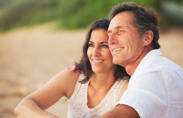 Man and woman sharing healthy smiles after replacing missing teeth