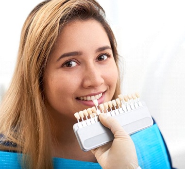 Cosmetic dentist in Charleston holding a row of porcelain veneer color options to smile