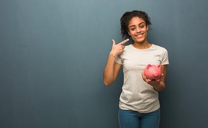 woman holding a piggy bank and pointing to her smile 